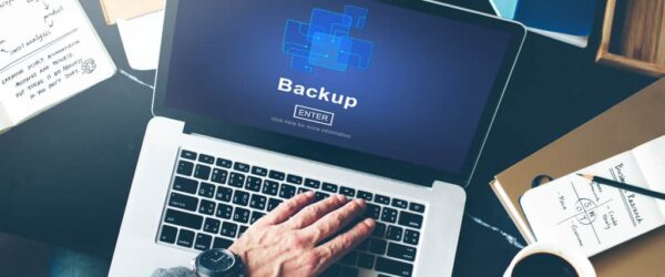 carbonite-backup-partner A hand on a laptop keyboard with a screen showing Backup.