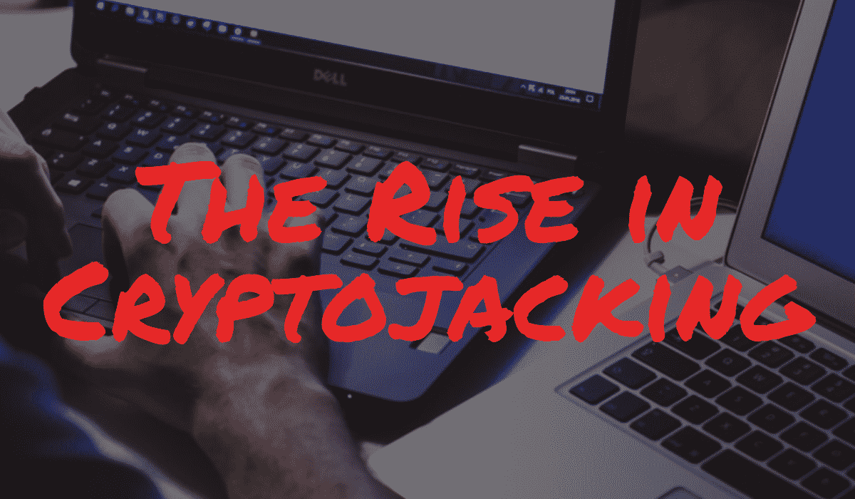 The Rise in Cryptojacking Banner - Featuring two laptops, with a hand typing on one