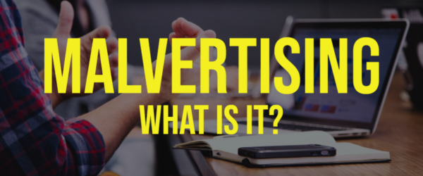 BSN-Blog-2.25.20 Malvertising – What Is It? Banner - Featuring a person at a table with a computer and laptop on it