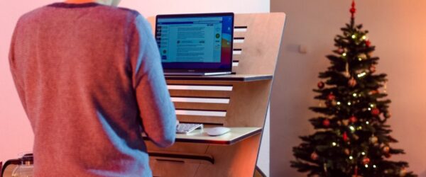 An individual conducting a cybersecurity audit in Wrightsville Beach NC, using a computer placed on a wooden stand, with a festive Christmas tree in the background.