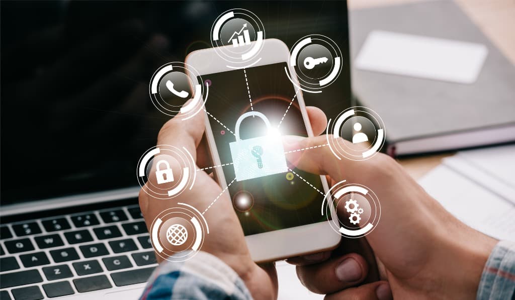 Hands holding a phone showing cybersecurity icons, representing Wilmington IT security measures.