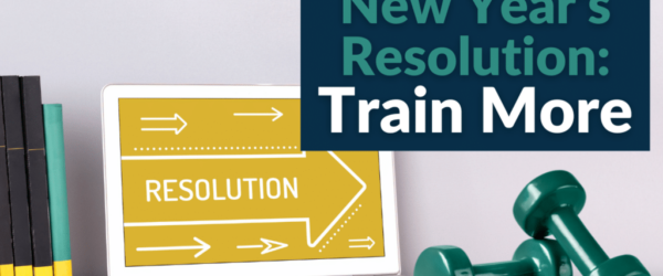 Weights next to a laptop on a desk with the text "New Year's Resolution: Train More."