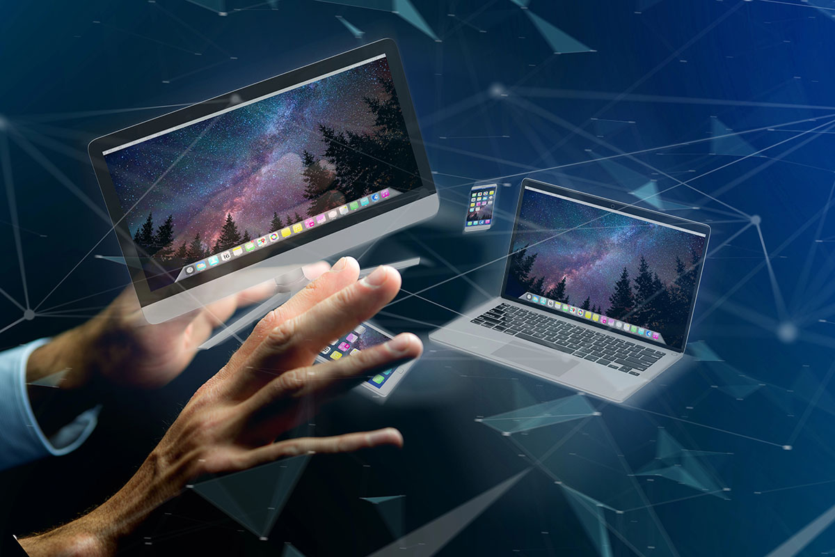 A person's hand reaches towards floating digital screens displaying a starry night sky, alongside various electronic devices like a laptop and smartphone, set against a futuristic, blue-toned background with abstract geometric shapes.