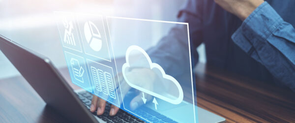 Cloud Computing Concept A person using a laptop with a blue sky background, interacting with digital icons representing data analysis and cloud computing.