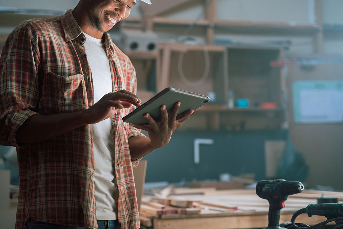 A man using a tablet in a furniture manufacturing plant.
