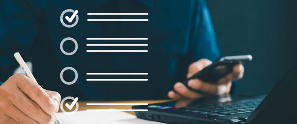 Compliance Checklist A person writing in a notebook with a pen while holding a smartphone, next to a laptop. Three checklist items are illustrated, with one item marked as complete.