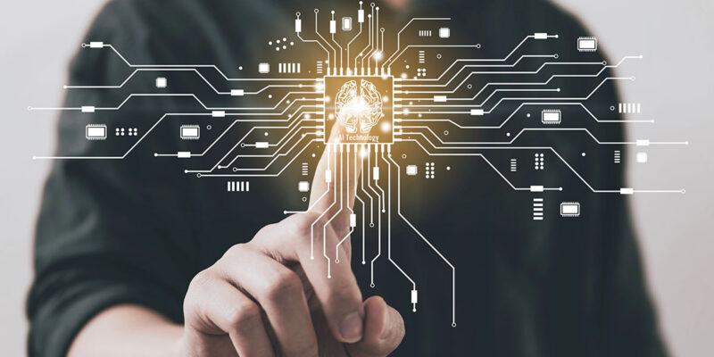 A person in a dark shirt touches a glowing circuit board with lines connecting various electronic components, featuring an icon of a brain labeled "AI Technology" at the center.