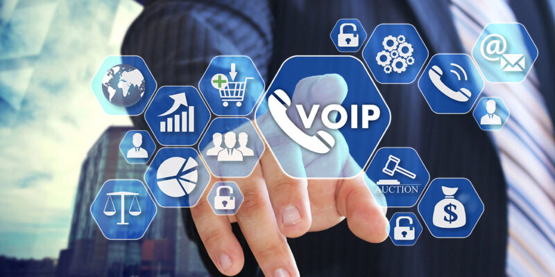 A businessman in a suit points towards a virtual touchscreen displaying various icons related to VoIP, communication, analytics, and online services.