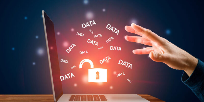 A hand reaches toward a laptop displaying an open padlock and multiple instances of the word "DATA" floating around in a glowing, digital environment.