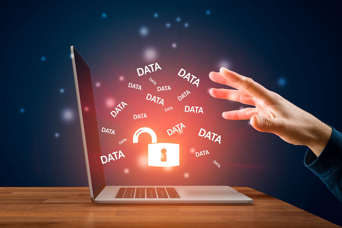 A hand reaches toward a laptop displaying an open padlock and multiple instances of the word "DATA" floating around in a glowing, digital environment.