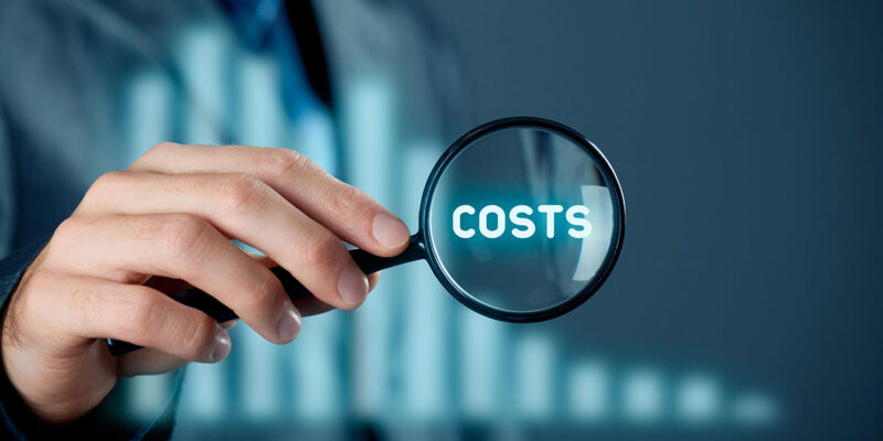 A person in a suit holds a magnifying glass over the word "COSTS," surrounded by a blurred background suggesting a business context.