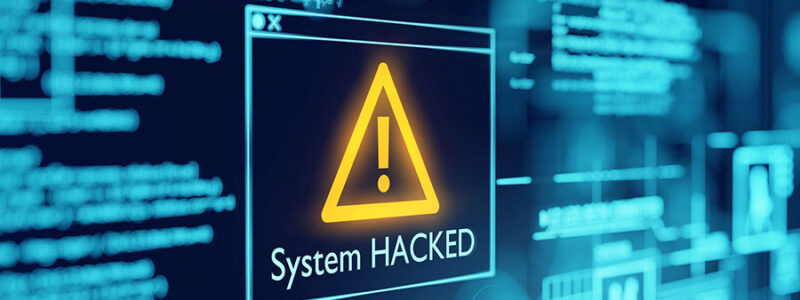 A digital display shows a warning message with an exclamation mark stating "System HACKED" against a backdrop of blue circuit-like graphics and lines of code.