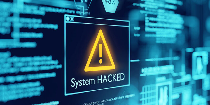 A digital display shows a warning message with an exclamation mark stating "System HACKED" against a backdrop of blue circuit-like graphics and lines of code.