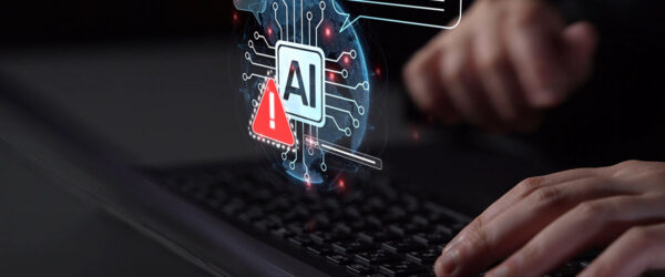 A person typing on a laptop with a digital graphic glowing above the keyboard showing an AI microchip icon next to a red warning sign.