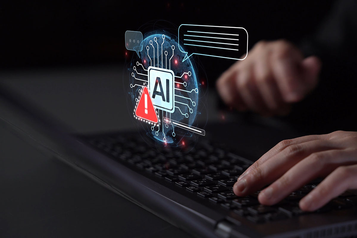 A person typing on a laptop with a digital graphic glowing above the keyboard showing an AI microchip icon next to a red warning sign.